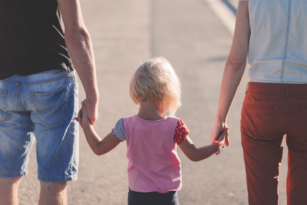 A family enjoying a sunny walk outdoors, hand-in-hand, symbolizing shared custody.