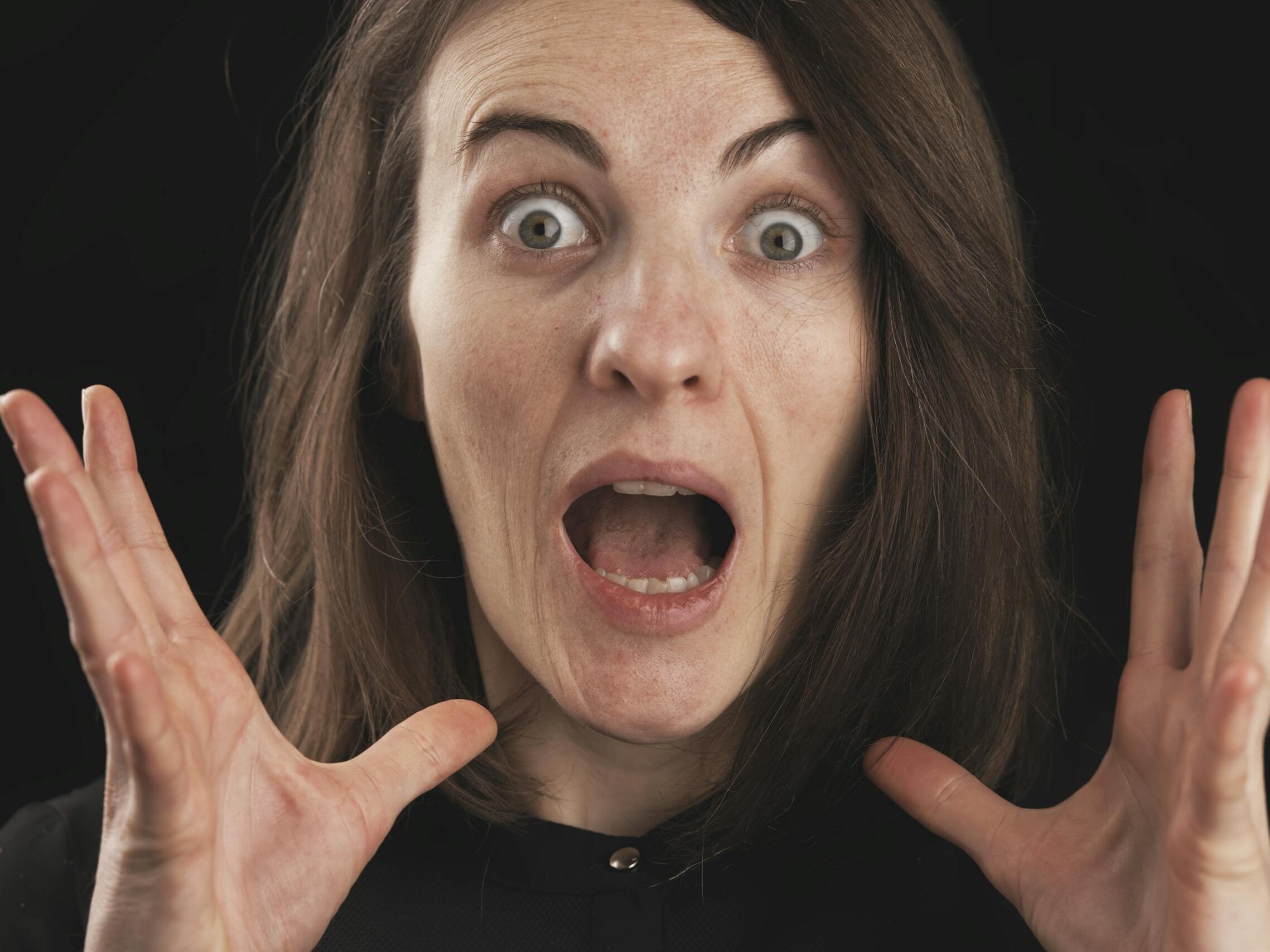 Close-up of a woman expressing shock and surprise with wide eyes and open mouth.